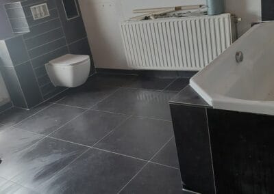 Badkamer met donkere tegelvloer en moderne afwerking